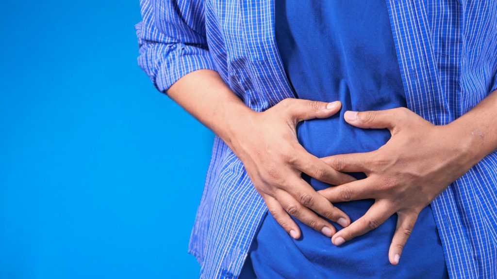 man in blue shirt holding his tummy due to bad Digestive Health 
